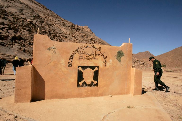 A military police walks at the French nuclear tests' site in In-Ekker near Ain Maguel, 170 km (106 miles) from the southern Algerian town of Tamanrasset, February 16, 2007. France should apologise for atom bomb tests in its former colony Algeria which were an atrocious crime that harmed humans and the environment, an Algerian official said on Tuesday.The Arabic script reads: