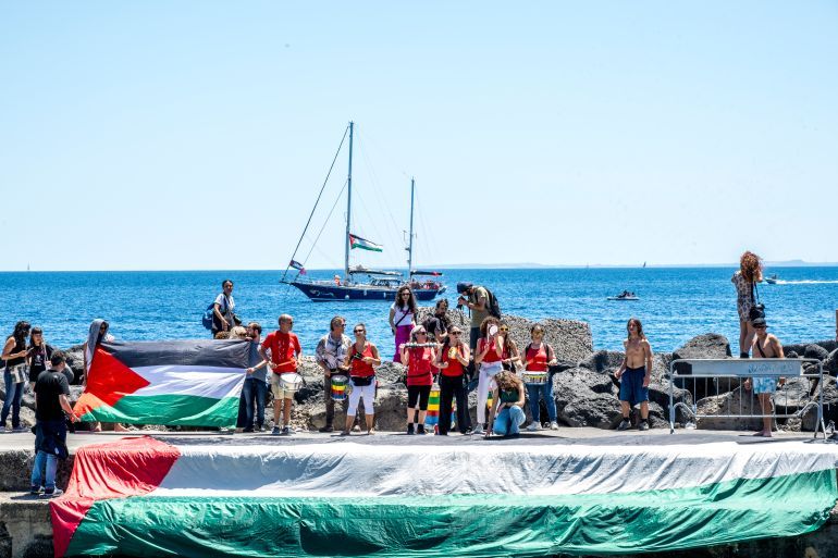 CATANIA, ITALY - JUNE 01: On the quay of San Giovanni Li Cuti, a group of activists greets the departure of the Madleen for Gaza with songs and Palestinian flags on June 01, 2025 in Catania, Italy. Swedish activist Greta Thunberg is among those who will attempt to sail to Gaza on a boat organized by the Freedom Flotilla Coalition (FFC), in a bid to break Israel's blockade of the Palestinian territory. Freedom Flotilla had to abort a previous journey in early May after it said its boat came under attack by drones in international waters near Malta. (Photo by Fabrizio Villa/Getty Images)