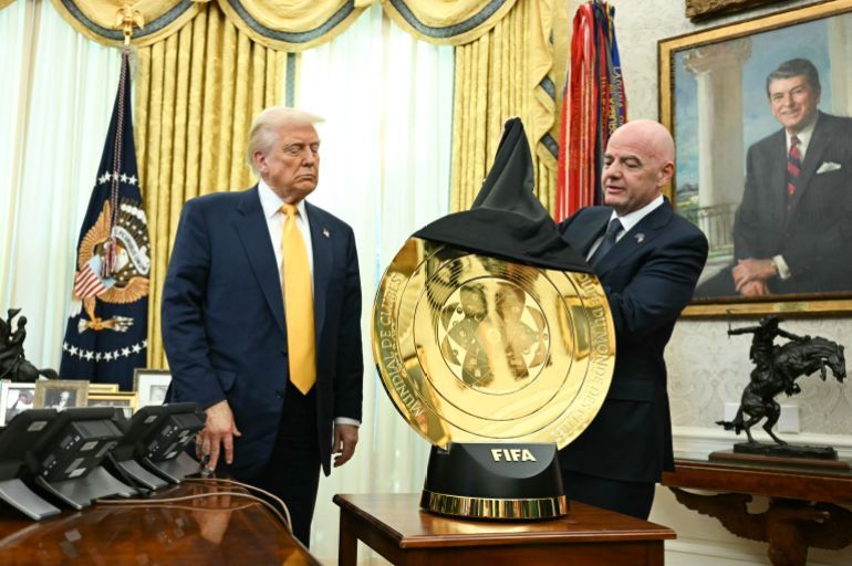US President Donald Trump watches as FIFA president (Fédération Internationale de Football Association) Gianni Infantino unveils the new FIFA Club World Cup trophy in the Oval office of the White House, in Washington, DC, on March 7, 2025. (Photo by Jim WATSON / AFP)