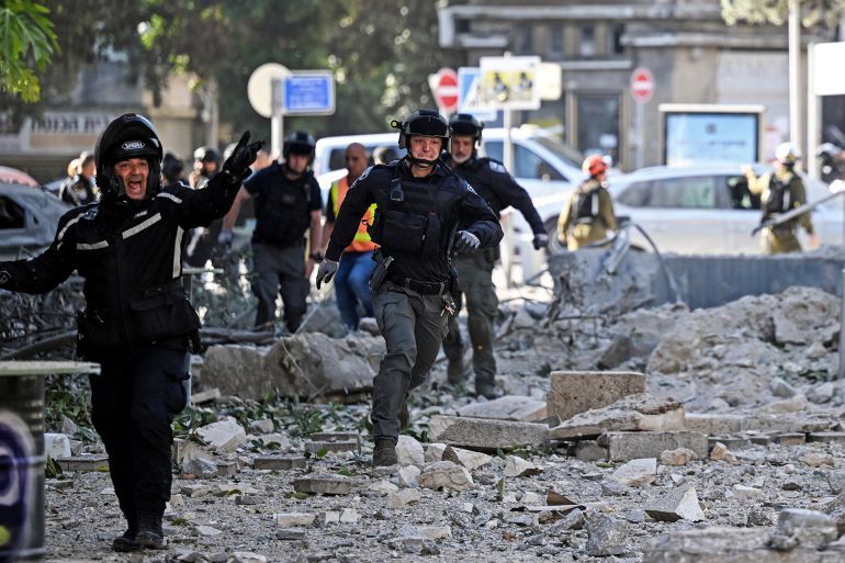 Security forces run as a second siren sounds at an impacted site, as they work following an earlier missile attack from Iran, amid the Iran-Israel conflict in Haifa, Israel June 22, 2025. REUTERS/Rami Shlush ISRAEL OUT. NO COMMERCIAL OR EDITORIAL SALES IN ISRAEL.