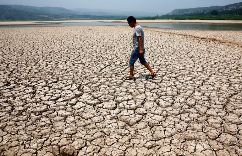 A man walks through the dried-up bed of a reservoir in Sanyuan county, Shaanxi province July 30, 2014. Lingering droughts in most parts of China have affected millions of hectares of agricultural crops, the State Flood Control and Drought Relief Headquarters said on Wednesday. Picture taken in July 30, 2014. REUTERS/Stringer (CHINA - Tags: ENVIRONMENT DISASTER TPX IMAGES OF THE DAY) CHINA OUT. NO COMMERCIAL OR EDITORIAL SALES IN CHINA