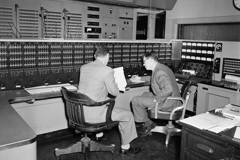 FILE - Two employees huddle in the Voice of America's radio control room in New York, Feb. 27, 1953, through which all voice broadcasts. (AP Photo/John Rooney, File)