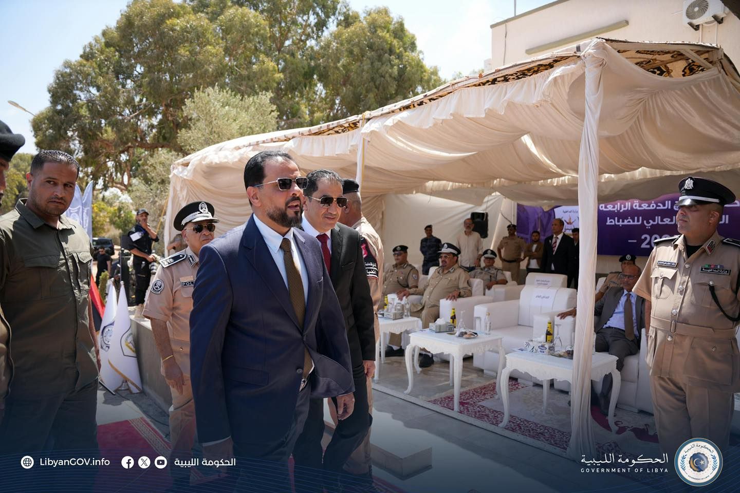 May be an image of ‎13 people, dais, wedding and ‎text that says '‎الرابعه الدفعة الدفعةالرابعه العالي للضباط LibyanGOV.info 曲 f الحكومة الليبية الليبية الحكومة الحكومةالليية O COVERNNENTOFLIBYA‎'‎‎
