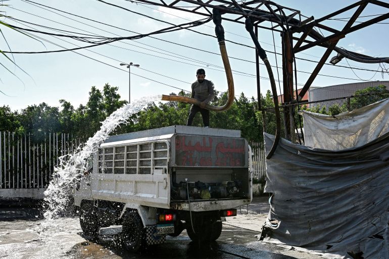 A man fills a tanker delivery truck with water from an underground water well distribution facility in Beirut on July 3, 2025.