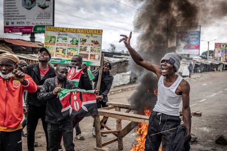 TOPSHOT - Protesters chant anti-government slogans and wave Kenyan flags beside a burning barricade blocking a road during Saba Saba Day protests in Nairobi, on July 7, 2025. Kenya marked its fight for democracy on July 7, 2025 with police blocking main roads in Nairobi ahead of potential protests, after last month's demonstrations descended into violent clashes. Saba Saba Day marks the uprising on July 7, 1990 when Kenyans demanded a return to multi-party democracy after years of autocratic rule by then-president Daniel arap Moi. (Photo by Luis TATO / AFP)