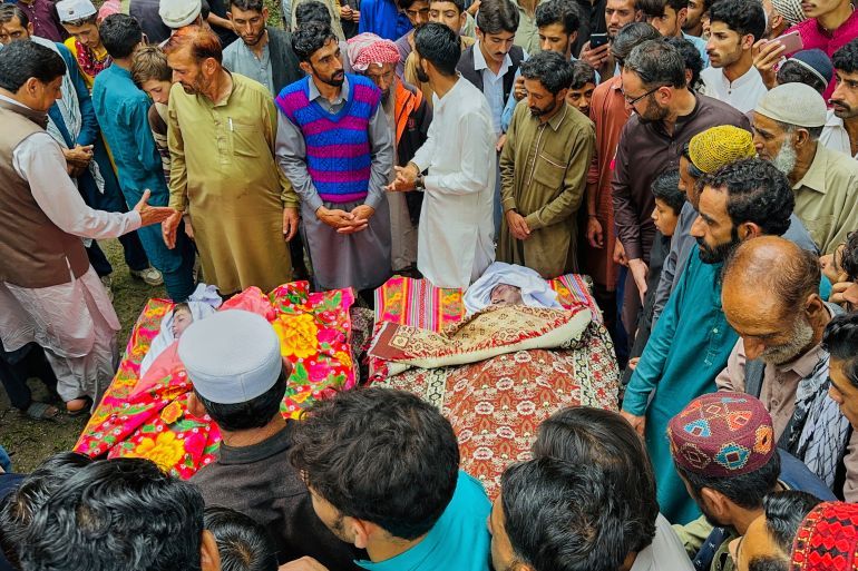 People gather around the bodies of the victims of a cloudburst incident, sudden intense downpours, after funeral prayers, in Naryan Behak village near Muzaffarabad, the main town of Pakistan's controlled Kashmir, Friday, Aug. 15, 2025. (AP Photo/M.D. Mughal)