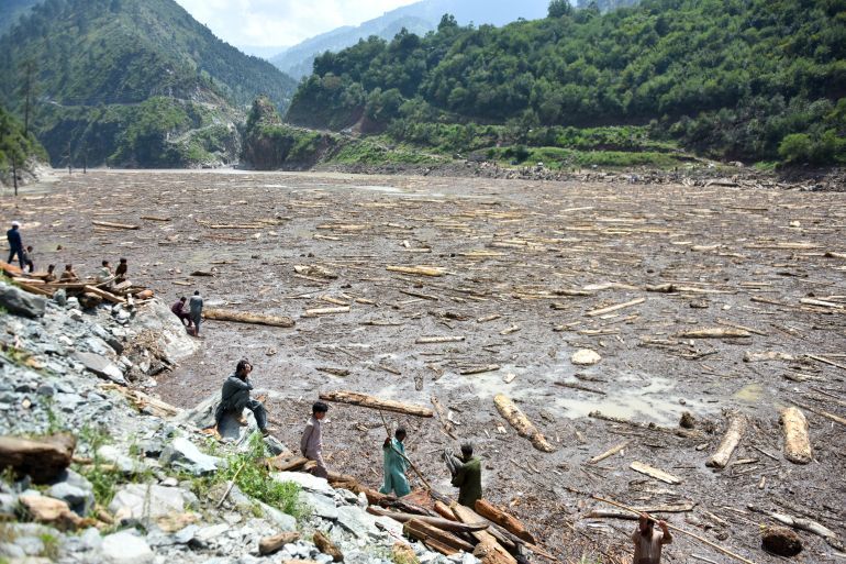 TOPSHOT - Locals collect woods from Noseri Dam near Muzaffarabad, the capital of Pakistan-administered Kashmir, on August 16, 2025, a day after flash floods.