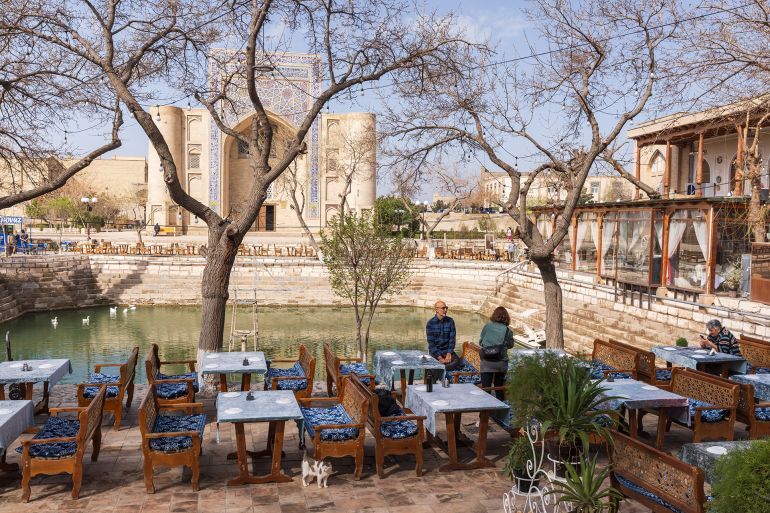 Bukhara, Uzbekistan - March 27, 2024: People are at the Lab-i Hauz Khanqah square, Nadir Divan-Beghi madrasa is on the background; Shutterstock ID 2627087131; purchase_order: aj; job: ; client: ; other:
