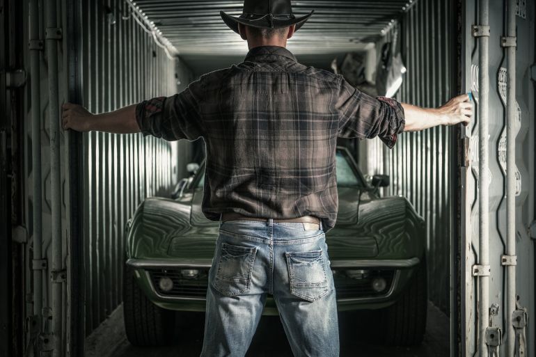 Caucasian Cowboy in His 40s Opening His Storage with Muscle Classic Cars Inside. Ready to Get the Project Started.
