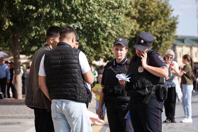 Moscow, Russia - August 14, 2024: Russian police officers checking the documents of migrants on Red Square; Shutterstock ID 2503233125; purchase_order: aj; job: ; client: ; other: