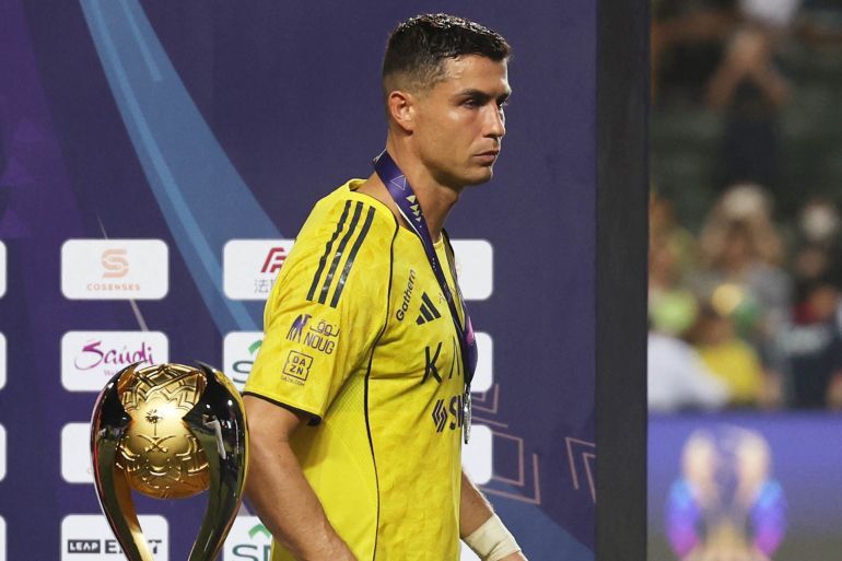 Soccer Football - Saudi Super Cup - Final - Al Nassr v Al Ahli - Hong Kong Stadium, Hong Kong, China - August 23, 2025 Al Nassr's Cristiano Ronaldo walks past the trophy on the podium with his medal as he looks dejected after the match REUTERS/Tyrone Siu