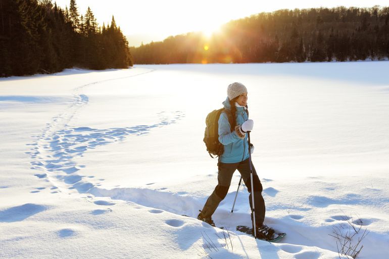 Winter sport activity. Woman hiker hiking with backpack and snowshoes snowshoeing on snow trail forest in Quebec, Canada at sunset. Beautiful landscape with coniferous trees and white snow.; Shutterstock ID 514939690; purchase_order: aj; job: ; client: ; other: