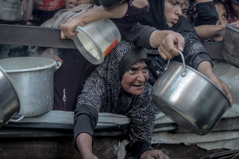 GAZA CITY, GAZA - JULY 23: Palestinians carrying pans, gather to receive hot meals, distributed by a charity organization in Gaza City, where residents are struggling to access food due to the ongoing Israeli blockade and attacks in Gaza City, Gaza on July 23, 2025. (Photo by Saeed M. M. T. Jaras/Anadolu via Getty Images)