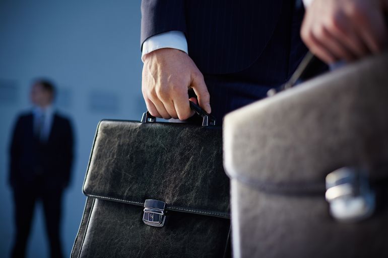 Cropped image of business partners carrying briefcases on the foreground while their colleague standing on the background ; Shutterstock ID 178332941; purchase_order: aj; job: ; client: ; other:
