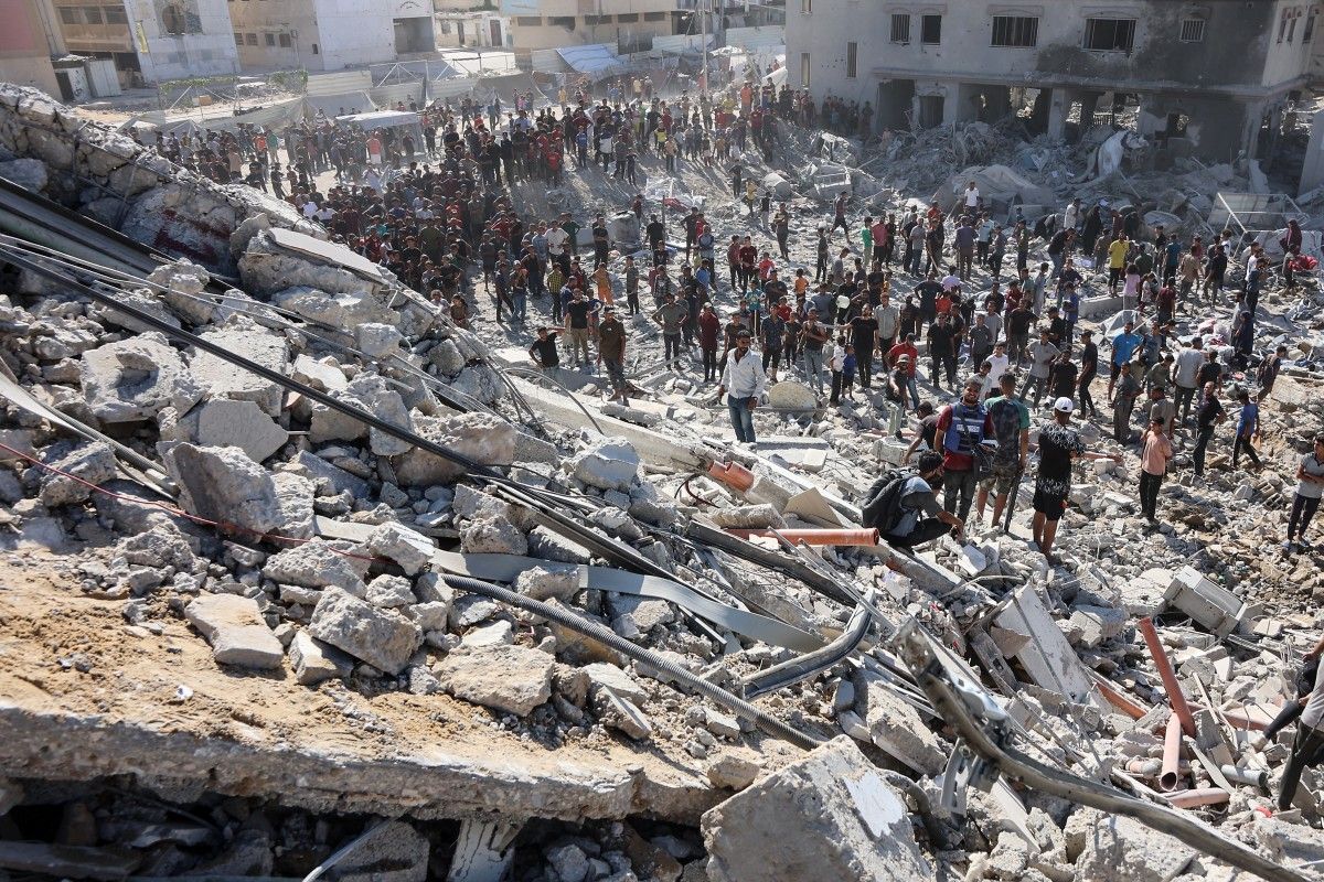 فلسطينيون يتفقدون أنقاض مبنى يسمى برج الرؤيا في منطقة الرمال بمدينة غزة بعد قصف الجيش الإسرائيلي له (أ ف ب).