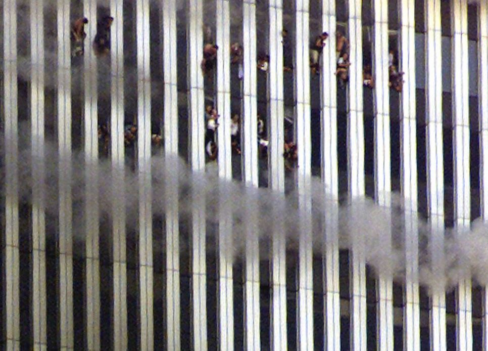 أشخاص ينظرون من البرج الشمالي المحترق لمركز التجارة العالمي، 11 سبتمبر 2001، (رويترز).